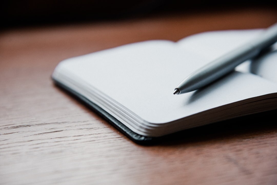 Open notebook with a small plant on a wooden desk